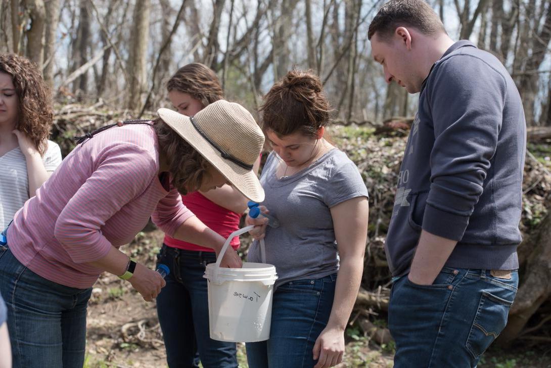 Students and Dr. 桑德斯检查在坎菲尔德保护区溪流中发现的一桶标本